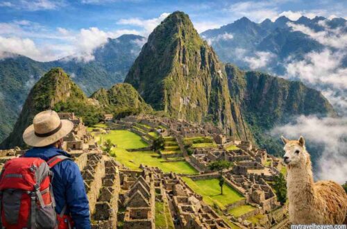 Traveler overlooking Machu Picchu ruins with mountain backdrop.