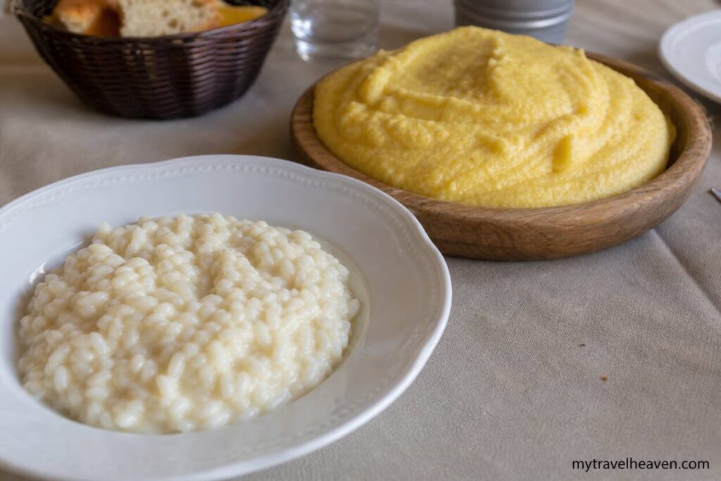 Creamy risotto and traditional polenta served on a rustic table in Northern Italy with soft natural lighting.