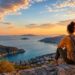 Traveler watching sunset over coastline after life-changing journey.