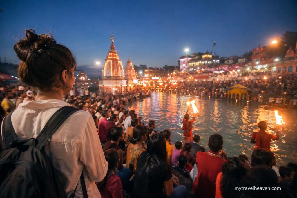 Traveler experiencing a vibrant cultural festival by a riverside at night with glowing ceremonial lights, crowds, and illuminated temples.